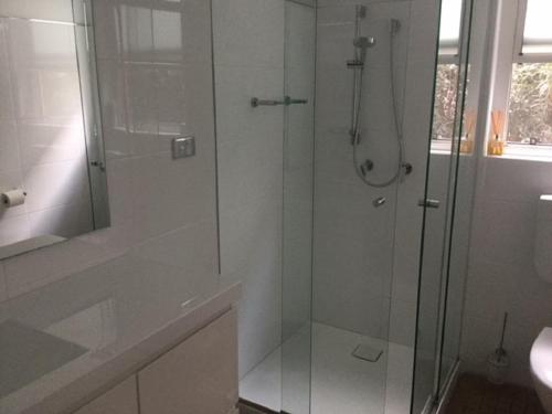 a bathroom with a shower with a glass door at Dutchies Beachside Retreat in Nelson Bay