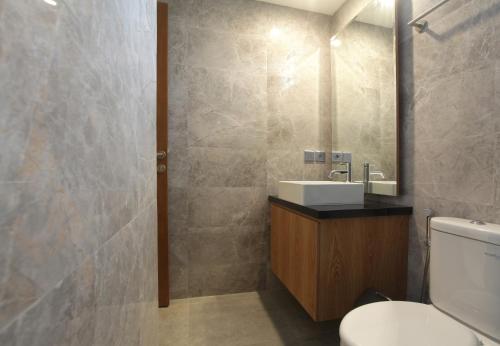 a bathroom with a toilet and a sink and a mirror at Matahari Bungalow in Legian