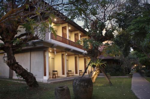 a building with a balcony and tables and trees at Matahari Bungalow in Legian
