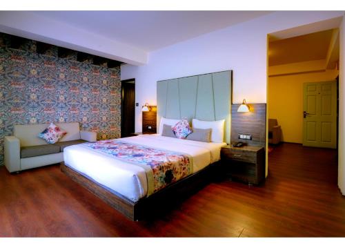 a bedroom with a large white bed and a couch at Udaan Woodberry Hotel & Spa in Gangtok