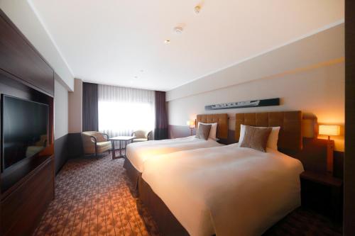 a hotel room with two beds and a flat screen tv at Kyoto Century Hotel in Kyoto