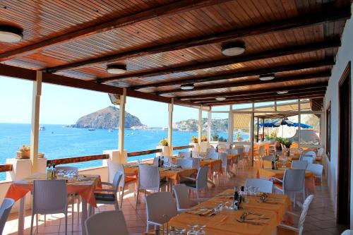 a restaurant with tables and chairs and the ocean at Hotel La Gondola in Ischia