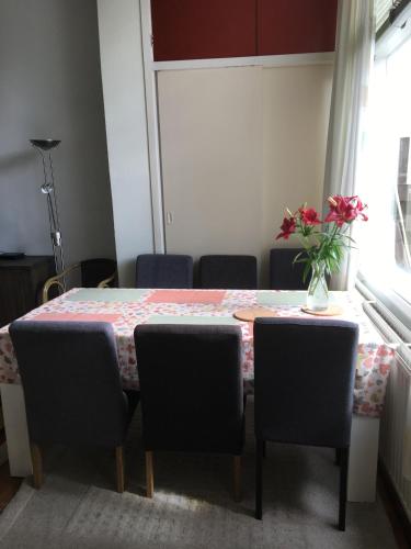 a dining room table with chairs and a vase of flowers on it at Cosy Apartment De Pijp Bed and Breakfast in Amsterdam