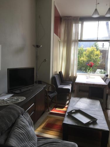 ein Wohnzimmer mit einem Sofa und einem TV in der Unterkunft Cosy Apartment De Pijp Bed and Breakfast in Amsterdam