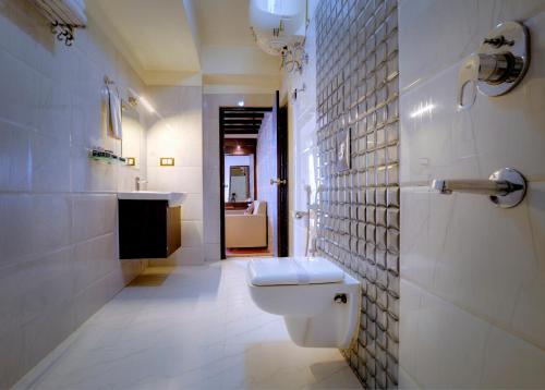 a white bathroom with a toilet and a sink at Udaan Woodberry Hotel & Spa in Gangtok