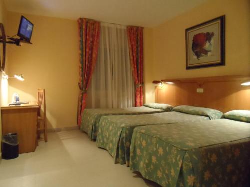 a hotel room with two beds and a television at Hotel Rey Arturo Burgos in Villagonzalo-Pedernales