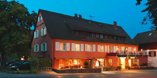 a large red house with a car parked in front of it at Insel-Hof Reichenau Hotel-garni in Reichenau