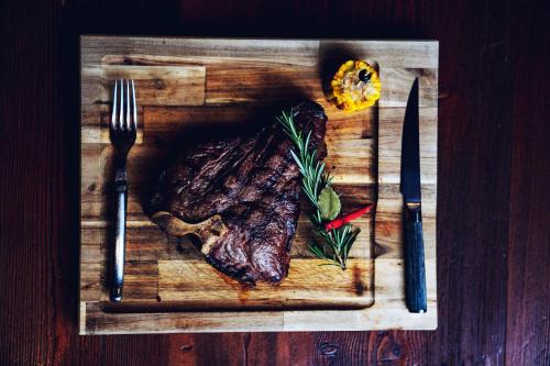 a steak on a cutting board with a fork and knife at Thehotel at LIPPISCHER HOF in Bad Salzuflen