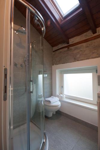 a bathroom with a toilet and a glass shower at Castello di Vezio in the Village in Varenna