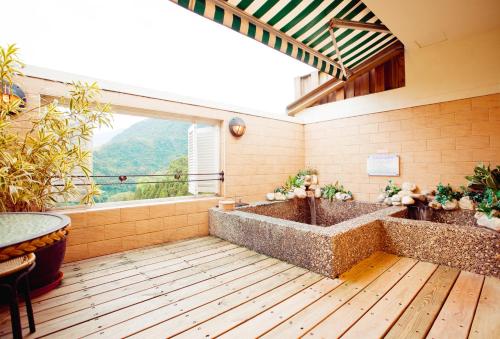 ein großes Bad mit einer Badewanne und einem großen Fenster in der Unterkunft Mi Jing Garden Spring Resort in Wulai