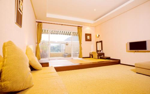 Mi Jing Garden Spring Resort في ويلاي: غرفة معيشة بها أريكة وتلفزيون
