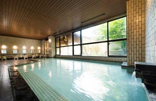 een groot zwembad in een gebouw met ramen bij Hotel Tangram in Shinano