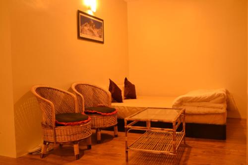 1 dormitorio con 1 cama, 2 sillas y mesa en Pradhan House - Home Stay with Garden, en Bhaktapur