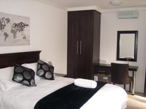 a bedroom with a bed with black and white pillows at La Coscello Guest House in Edenvale