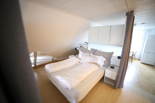 - une chambre avec un lit doté de draps et d'oreillers blancs dans l'établissement BraMy Apartments The LUX View, à Tromsø
