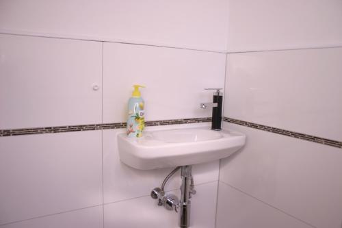 a white sink in a white tiled bathroom at Stumpf Verpachtung Gbr in Treuchtlingen