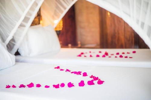 a pile of pink rose petals on a bed at VRclub Paje Palms Beach Resort in Paje