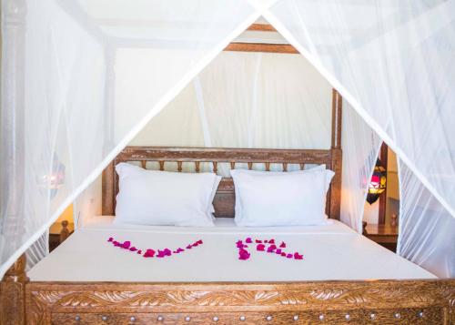 a bed with white sheets and pink flowers on it at VRclub Paje Palms Beach Resort in Paje