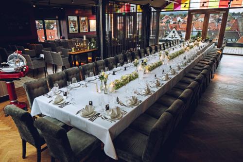 a long table in a restaurant with white tables and chairs at Der LIPPISCHE HOF in Bad Salzuflen