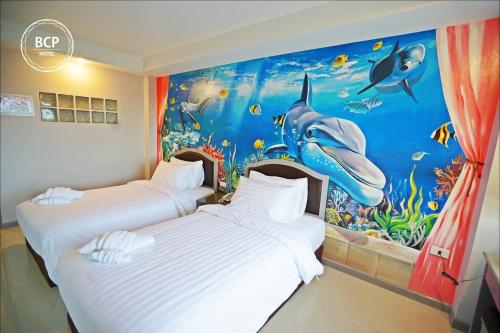 two beds in a hotel room with a shark mural at BCP Hotel in Ban Chang