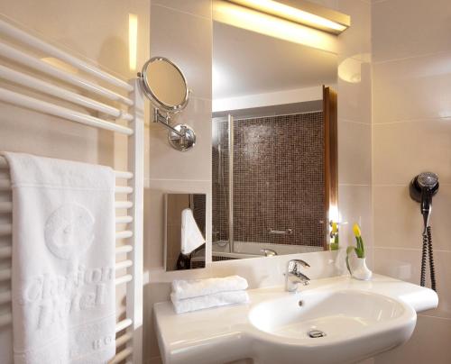 a white bathroom with a sink and a mirror at Clarion Congress Hotel Ostrava in Ostrava