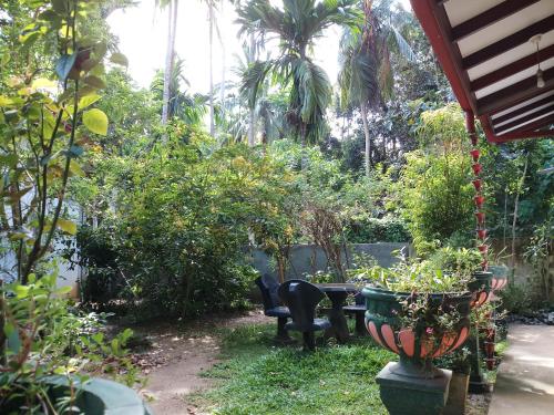 a garden with a table and chairs and trees at Piumi House in Hiriketiya