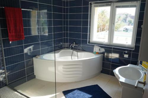 W wyłożonej niebieskimi kafelkami łazience znajduje się wanna i umywalka. w obiekcie Pascal Villa 7 nights 1 free w mieście Stari Grad