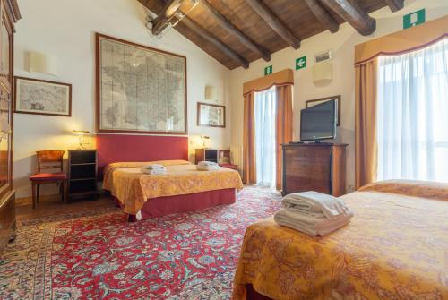 a hotel room with two beds and a television at Cà Palazzo Malvasia - BolognaRooms in Sasso Marconi