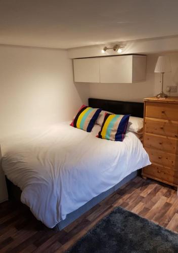 a bedroom with a white bed and a wooden dresser at Quality Accommodation in Leeds
