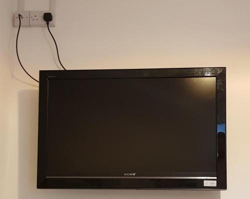Elle comprend une télévision à écran plat installée sur un mur. dans l'établissement Quality Accommodation, à Leeds