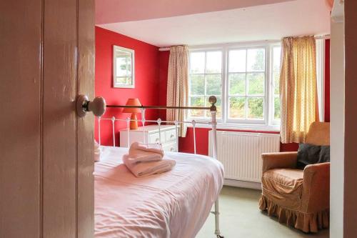 1 dormitorio con paredes rojas, 1 cama y 1 silla en 7 Whinlands, en Thorpeness