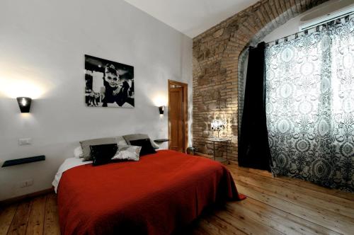 a bedroom with a red bed and a brick wall at Caesar's Rooms in Rome