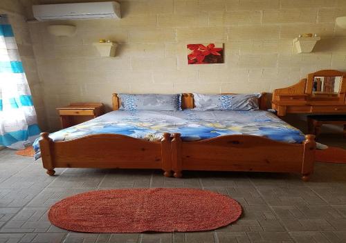 a bedroom with a wooden bed with a red bow on the wall at Ta' Karkar Villa Bed and Breakfast in Xagħra