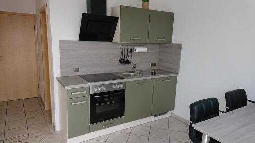 a kitchen with green cabinets and a sink and a table at Ferienwohnungen Eismecke in Bestwig