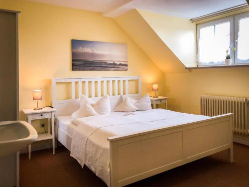 a bedroom with a large white bed with two windows at Hotel Hanseatic in Lübeck