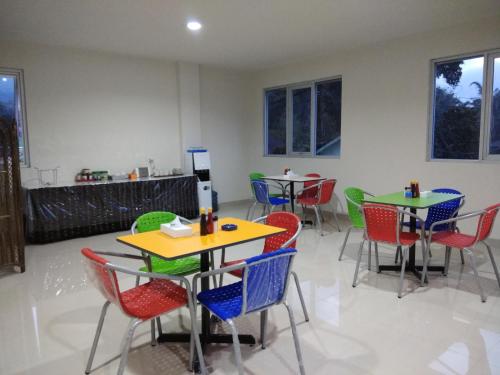 a dining room with tables and chairs and windows at Victory Hotel in Ruteng