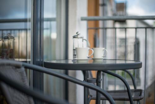 a table with two coffee cups and a glass jar at Lochend Park View Apartment in Edinburgh