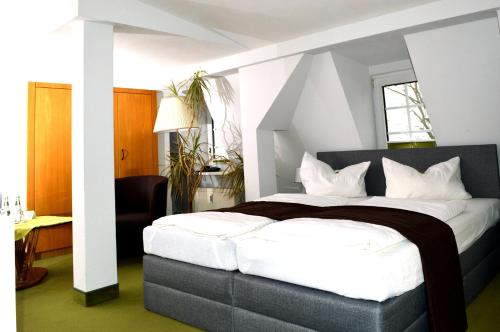 a bedroom with a large bed with white sheets at Strandhotel Buckow gut-Hotels SEE in Buckow