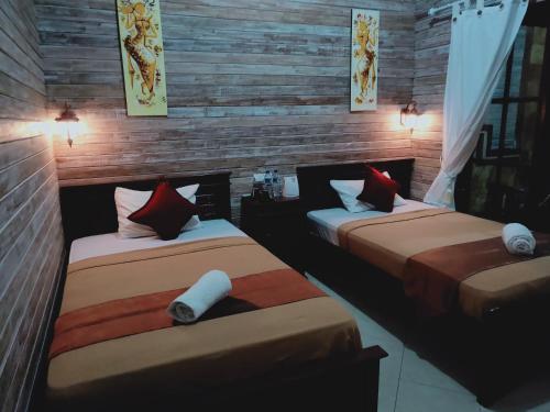 two beds in a room with wooden walls at Tiki bar and more in Nusa Lembongan