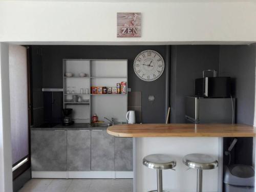 une cuisine avec un comptoir et une horloge au mur dans l'établissement Fleur d'orchidée studio 99, à Sens