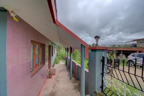 a pink building with a fence and a balcony at Chuppi Homestay in Madikeri