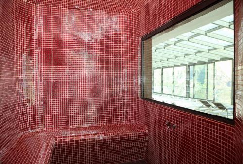 y baño con ducha de azulejos rojos y ventana. en Eira do Serrado - Hotel & Spa en Curral das Freiras