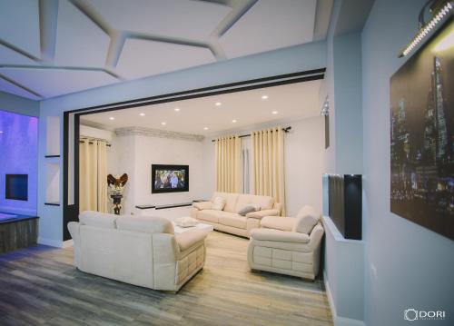 sala de estar con sofás blancos y TV en Apartament Suite Korca, en Korçë