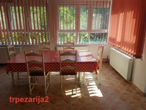 a dining room with a table and chairs and windows at "Popov VRT" Banoštor - kuća-vikendica na Dunavu-Fruskoj Gori in Banoštor