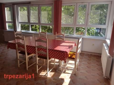 a dining room with a table and chairs and windows at "Popov VRT" Banoštor - kuća-vikendica na Dunavu-Fruskoj Gori in Banoštor