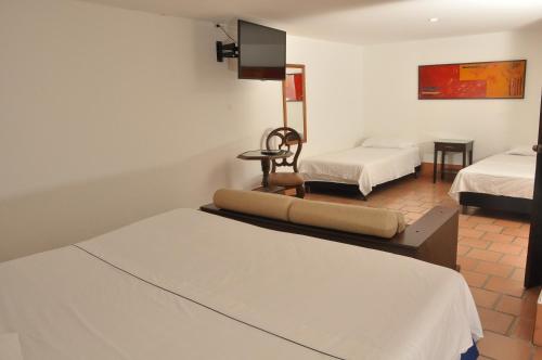 a room with two beds and a tv on the wall at Chrisban Hotel Boutique in Buga