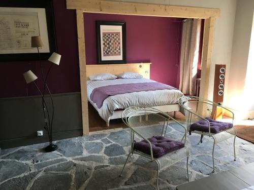 - une chambre avec un lit aux murs violets et 2 chaises dans l'établissement Gîte L Atelier du Peintre, à Saint-Maurice-de-Lignon