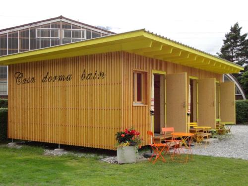 un edificio amarillo con mesas y sillas delante de él en Casa Dorma Bain, en Chur