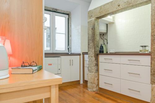 リスボンにあるTrombeta Apartment In Bairro Alto - Lisbonの白いキャビネットと木製テーブル付きのキッチン