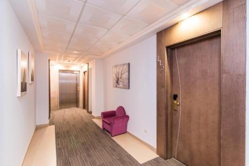 a hallway with a purple chair and a door at Hotel Baviera in Cala Ratjada